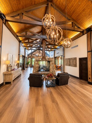 A spacious interior with a high ceiling, stone fireplace, leather seating, and wooden beams. - Escape the Arizona Heat + 2 King Suites + Bunk Room (Show Low)