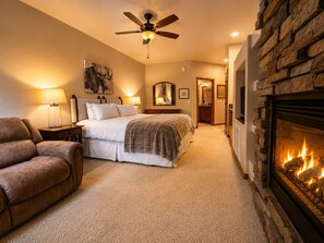 A bedroom with a bed, a fireplace, a ceiling fan, and a nightstand with a lamp. - Escape the Arizona Heat + 2 King Suites + Bunk Room (Show Low)