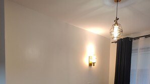 Ett rum med en säng, en soffa, ett litet runt bord och en väggmonterad lampa.