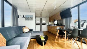 A modern living room with a sofa, coffee table, and dining area with chairs. - Boathouse With Lake View Terrace (Uitgeest)