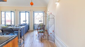 Een zithoek met een eettafel gedekt voor twee personen, een bank en een decoratieve scheidingswand met kaarsen.