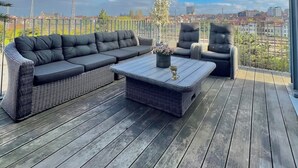 A rooftop terrace with a black sofa, two chairs, and a coffee table. - The Loft Brussels (Schaerbeek)