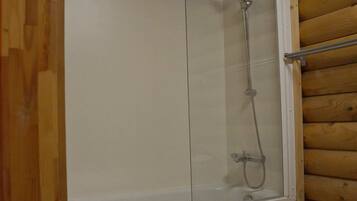 Une cabane en bois dotée d’une douche dans un espace clos par des parois de verre.