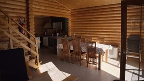 A log cabin interior with a dining area, kitchen, and a staircase.