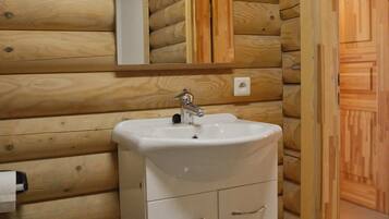 A wooden cabin-style bathroom with a sink, mirror, and cabinets.