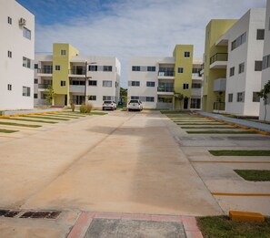 Un moderno edificio residencial con un patio central, estructuras de dos pisos y un sendero pavimentado.