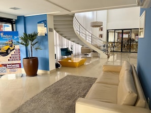 Un rebedor d'hotel modern, amb una escala, una zona de seients i una gran planta en test.