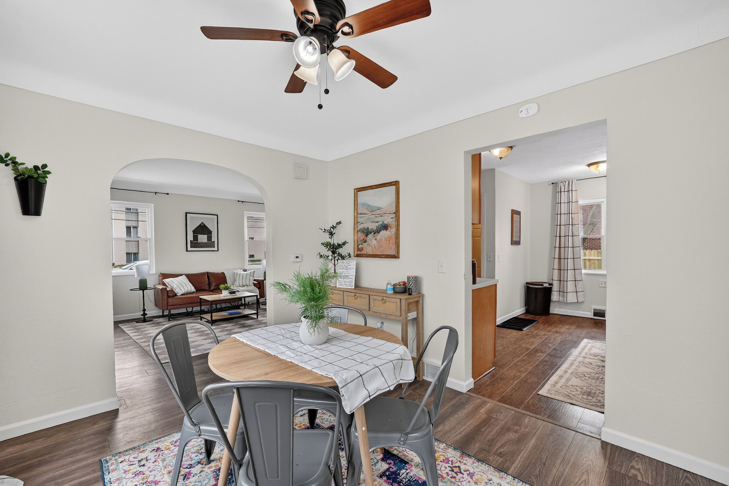 A dining area with a wooden table, metal chairs, a ceiling fan, and a view into another room.