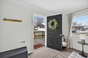 A room with a black door, a wooden bench, a small table with a lamp, and a view of the outside. - Updated 3br- Fiber Wi-Fi by Toledo Hospital & UT! (Toledo)