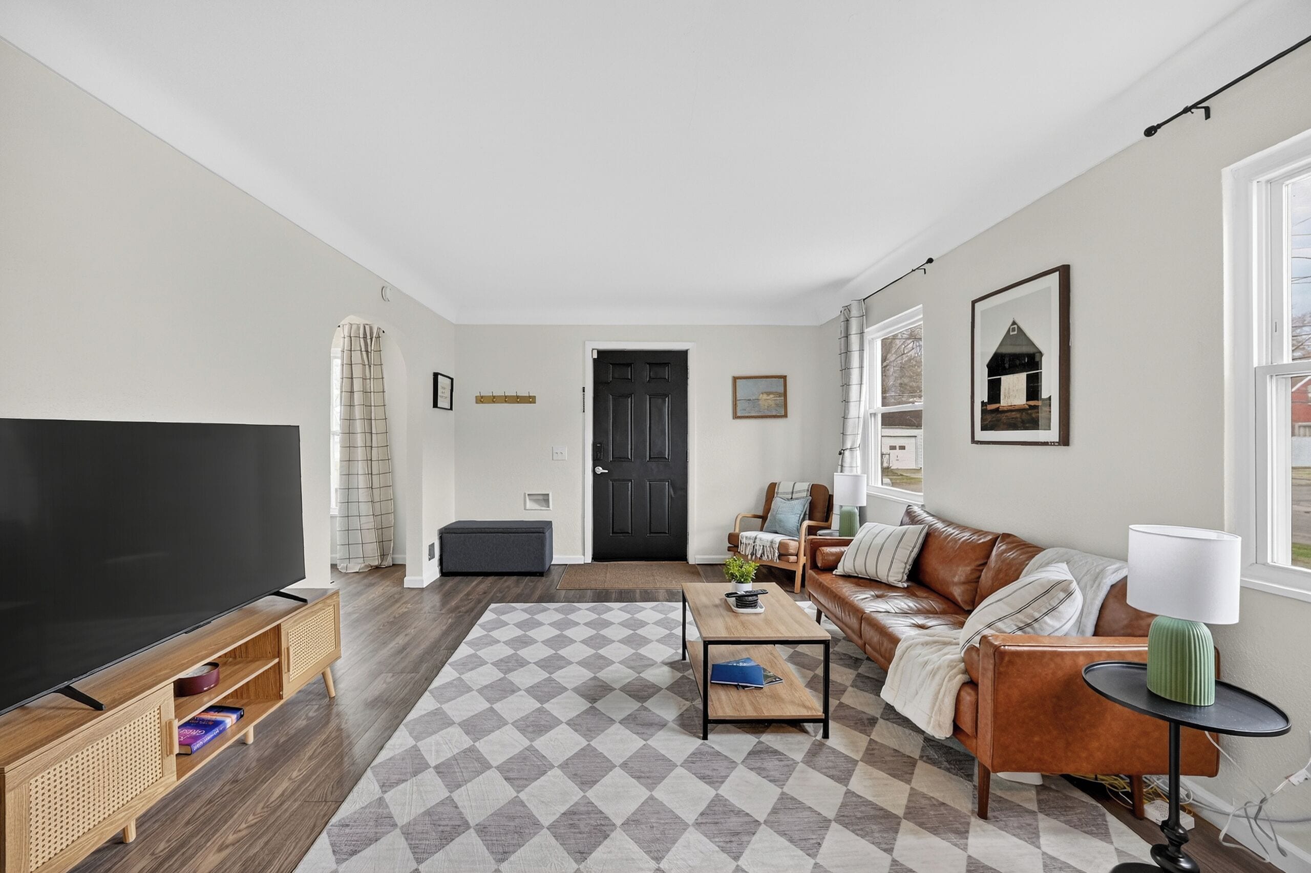 A living room with a TV, sofa, coffee table, and a patterned rug.