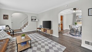 Una sala moderna con un sofá, una mesa de centro, un televisor y una escalera que lleva a otra habitación.