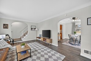 A modern living room with a sofa, coffee table, TV, and a staircase leading to another room. - Updated 3br- Fiber Wi-Fi by Toledo Hospital & UT! (Toledo)