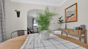 Un comedor con una mesa redonda, sillas, una planta en maceta, un cuadro y un armario de madera.