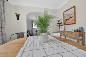 A dining area with a round table, chairs, a potted plant, a painting, and a wooden cabinet. - Updated 3br- Fiber Wi-Fi by Toledo Hospital & UT! (Toledo)