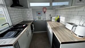 Una cocina compacta con azulejos blancos, una campana extractora negra, una ventana y un letrero que indica un mercado de mariscos.