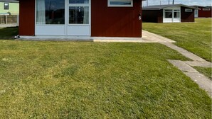 Un pequeño edificio de un piso con fachada roja, una puerta blanca y un ventanal grande.