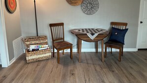 A room with a wooden table, two chairs, a lamp, and wall decorations.