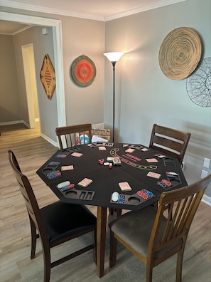 Una mesa redonda preparada para un juego, con fichas de póker y cartas, rodeada de sillas de madera.