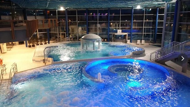 Une piscine intérieure dotée d’une fontaine centrale, le tout étant entouré d’une structure en verre.