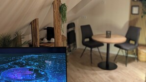 Une pièce aménagée avec une tente, comprenant une table ronde et des chaises, un écran de télévision et une plante suspendue.