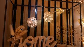 Un mur en bois avec des lattes verticales, des lampes sphériques décoratives et une enseigne en bois portant le mot « chez soi ».