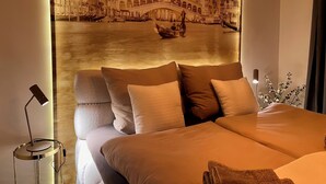 Une chambre d’hôtel avec un lit, des oreillers, une lampe de chevet et une fresque murale représentant un pont au-dessus de l’eau.