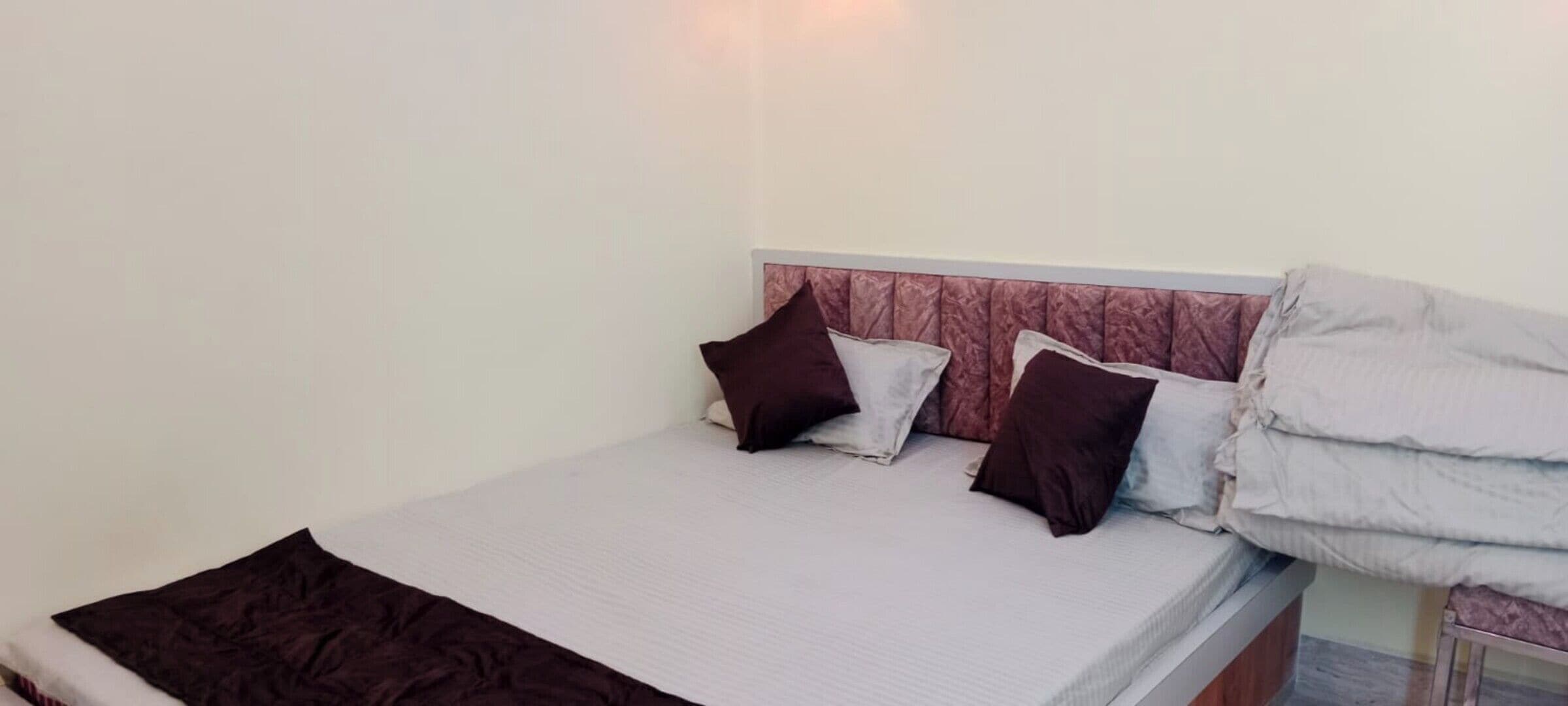 A single bed with a headboard, pillows, and a blanket.