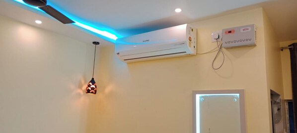Una habitación con aire acondicionado central, un termostato en la pared y una lámpara colgante.