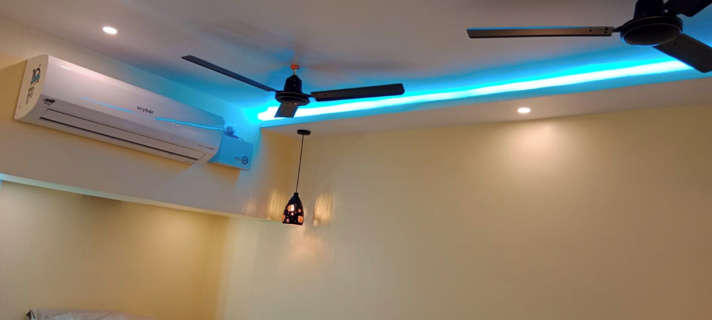 A room with a ceiling fan, an air conditioning unit, and a pendant light.