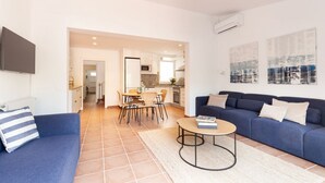 En moderne stue med en sofa, et sofabord og et spiseområde med stole og et bord.