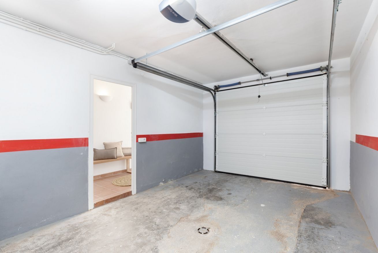 Un garage doté d’une porte à enroulement, d’un sol en béton et d’un mur aux couleurs rouge et grise.