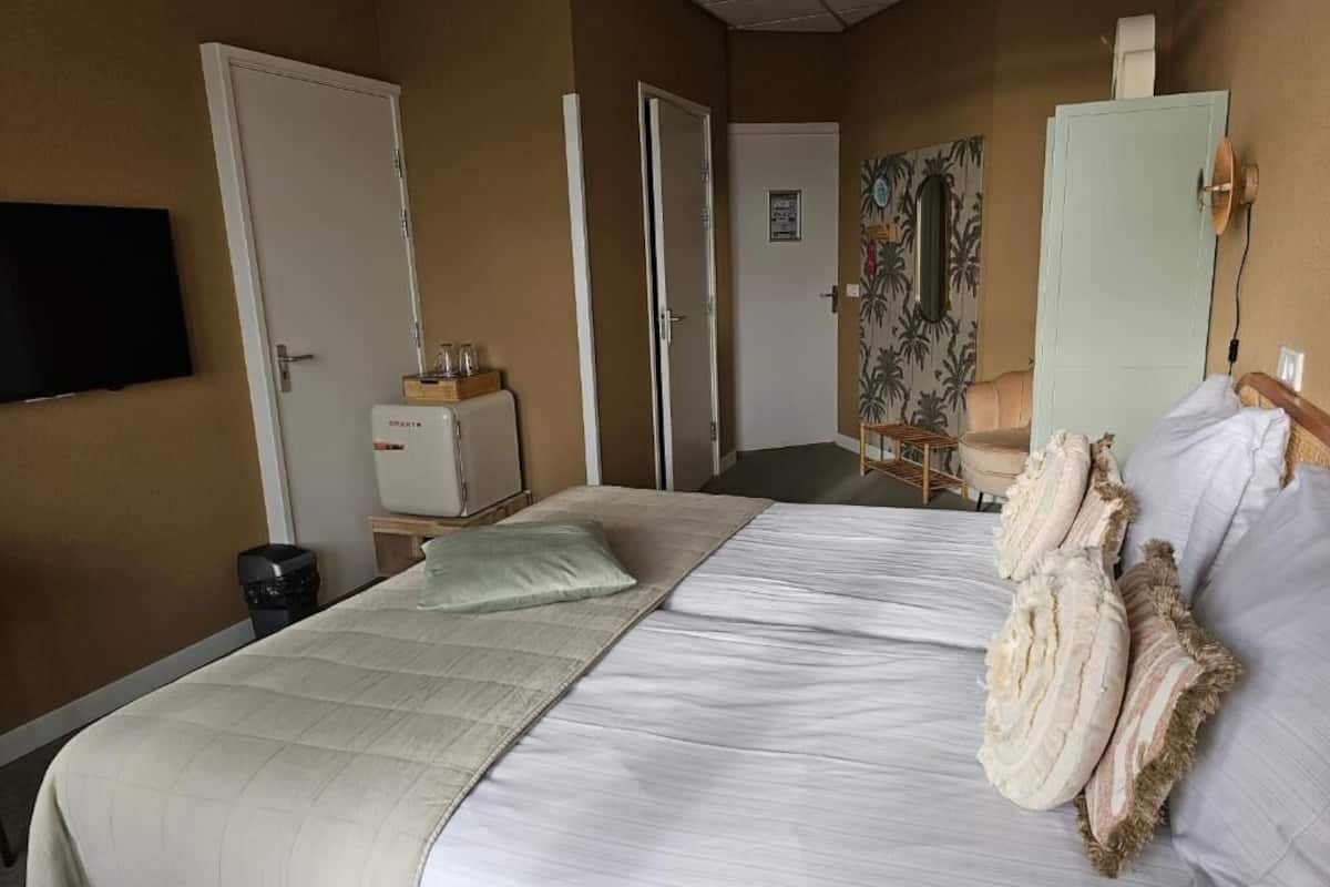 Una habitación de hotel con cama, televisor, minibar y puerta.