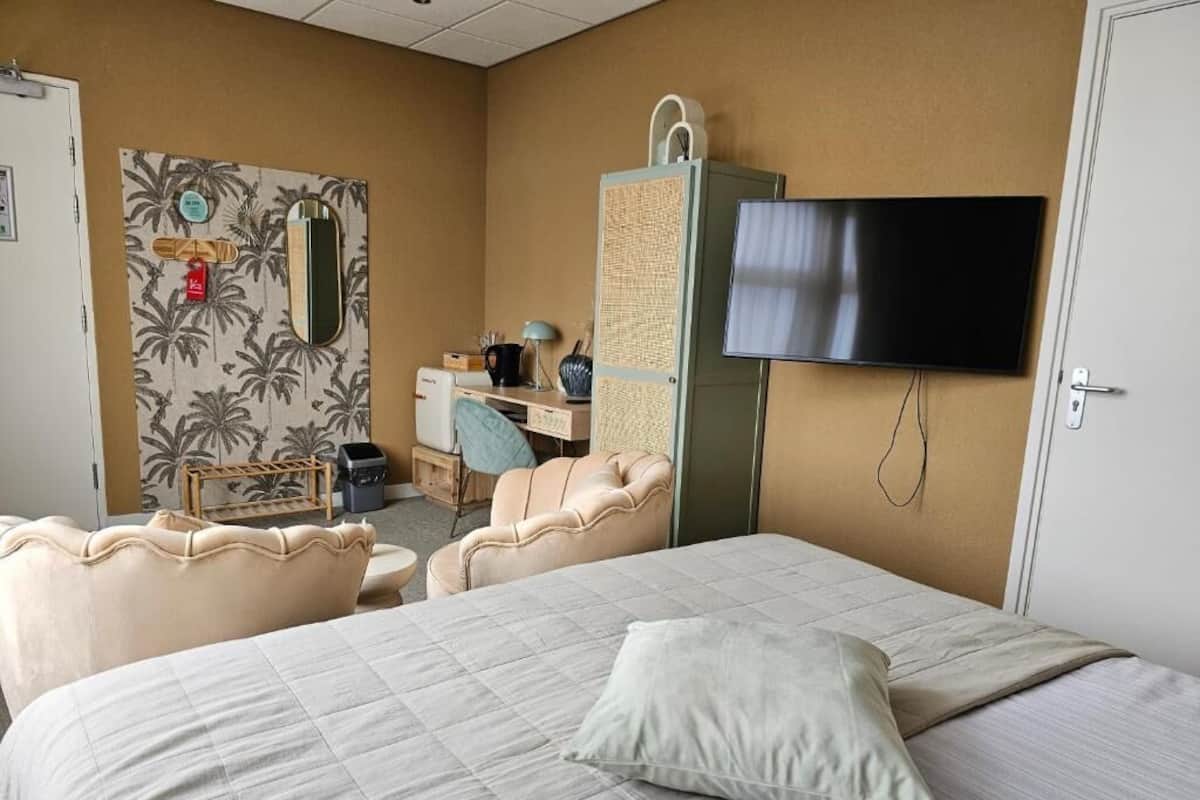 Una habitación de hotel con una cama, televisión, escritorio con silla y armario.