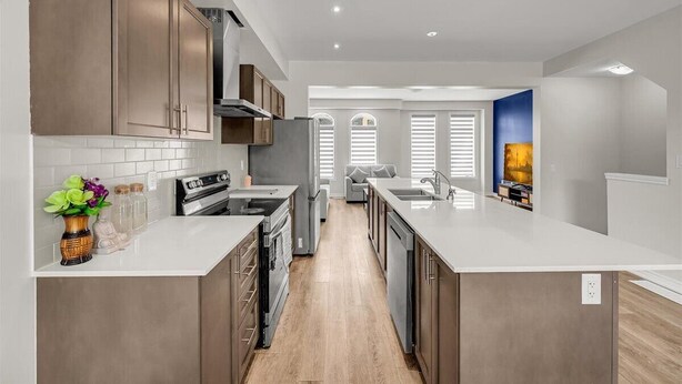 A modern kitchen with stainless steel appliances, a central island, and a view to the living area. - Brand New 4-BR Ensuite Townhouse | Netflix/Disney+ (Cambridge)