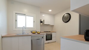 A modern kitchen with white cabinetry, a dishwasher, an oven, a microwave, and a clock on the wall. - Rosari II - Detached House with Parking (Vilassar de Mar)