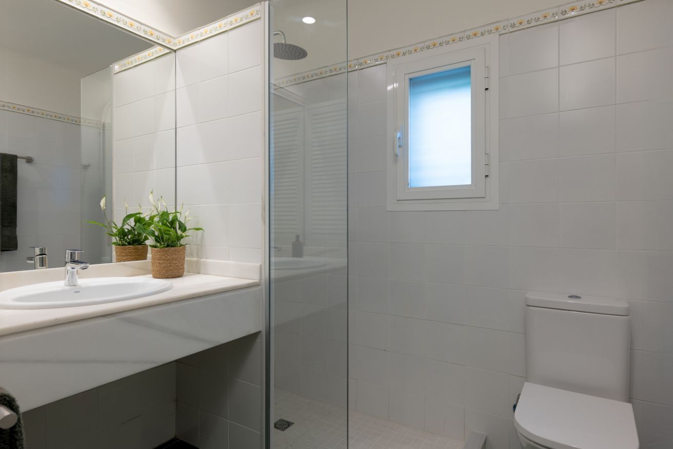 A modern bathroom with a glass-enclosed shower, a white sink, and a toilet.