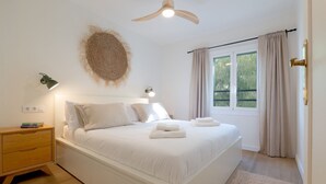 A bedroom with a bed, bedside tables, a ceiling fan, a window with curtains, and a wall-mounted light fixture. - Rosari II - Detached House with Parking (Vilassar de Mar)