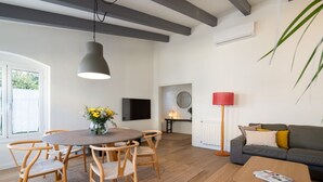 A modern living room with a dining area, a sofa, a coffee table, and a TV. - Rosari II - Detached House with Parking (Vilassar de Mar)