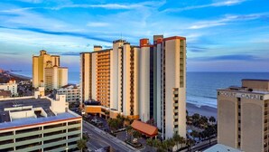 Un grand hôtel à plusieurs étages, doté d’un parking et offrant une vue sur la plage.