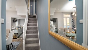 Eine Treppe führt zu einem Essbereich, in dem sich ein großer Spiegel im Raum spiegelt.
