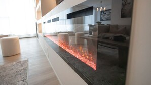 Un salon moderne avec une cloison en verre, une cheminée et un canapé.