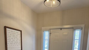Ein Zimmer mit einer Holzbank, einem gemusterten Teppich, einem gerahmten Motivationsspruch und einer weißen Tür mit Fenster.