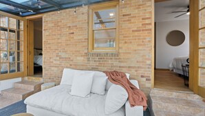 A room with a glass ceiling, a brick wall, a bed, and a dining area. - Walkable Downtown Sturgeon Bay - The Florist House (Sturgeon Bay)