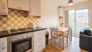 A modern kitchen with a checkered backsplash, a dining area with a table and chairs, and a view of the outside through a large window. - Modern 4 Bedroom Apartment In Limerick City (Limerick)