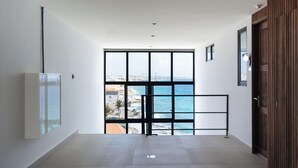 A hallway with a large window offering a view of the sea and buildings. - Bocobay Majestic Apartments (Willemstad)
