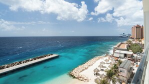 A coastal view with a pier, beach, and buildings. - Bocobay Majestic Apartments (Willemstad)