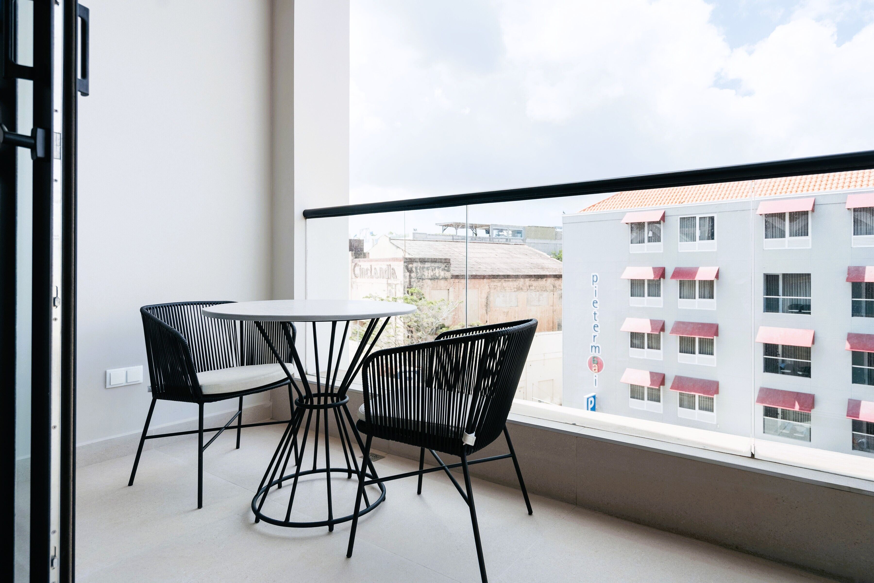 Ein Balkon mit Tisch und Stühlen, Blick auf Gebäude und einen klaren Himmel.
