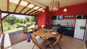 Una cucina moderna con una parete rossa, un tavolo da pranzo in legno e un'amaca all'esterno.