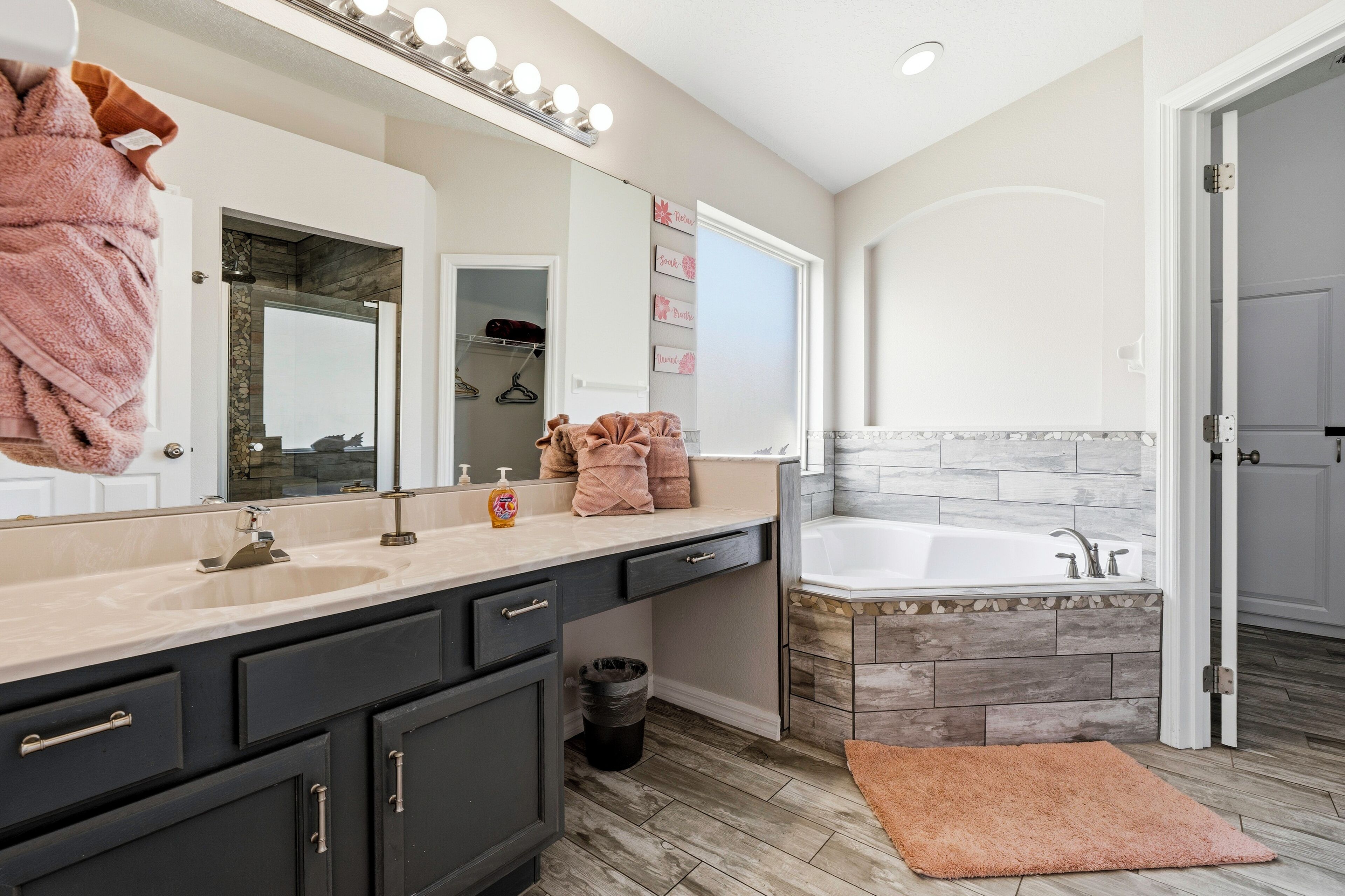 A modern bathroom with a large mirror, vanity, sink, and bathtub.