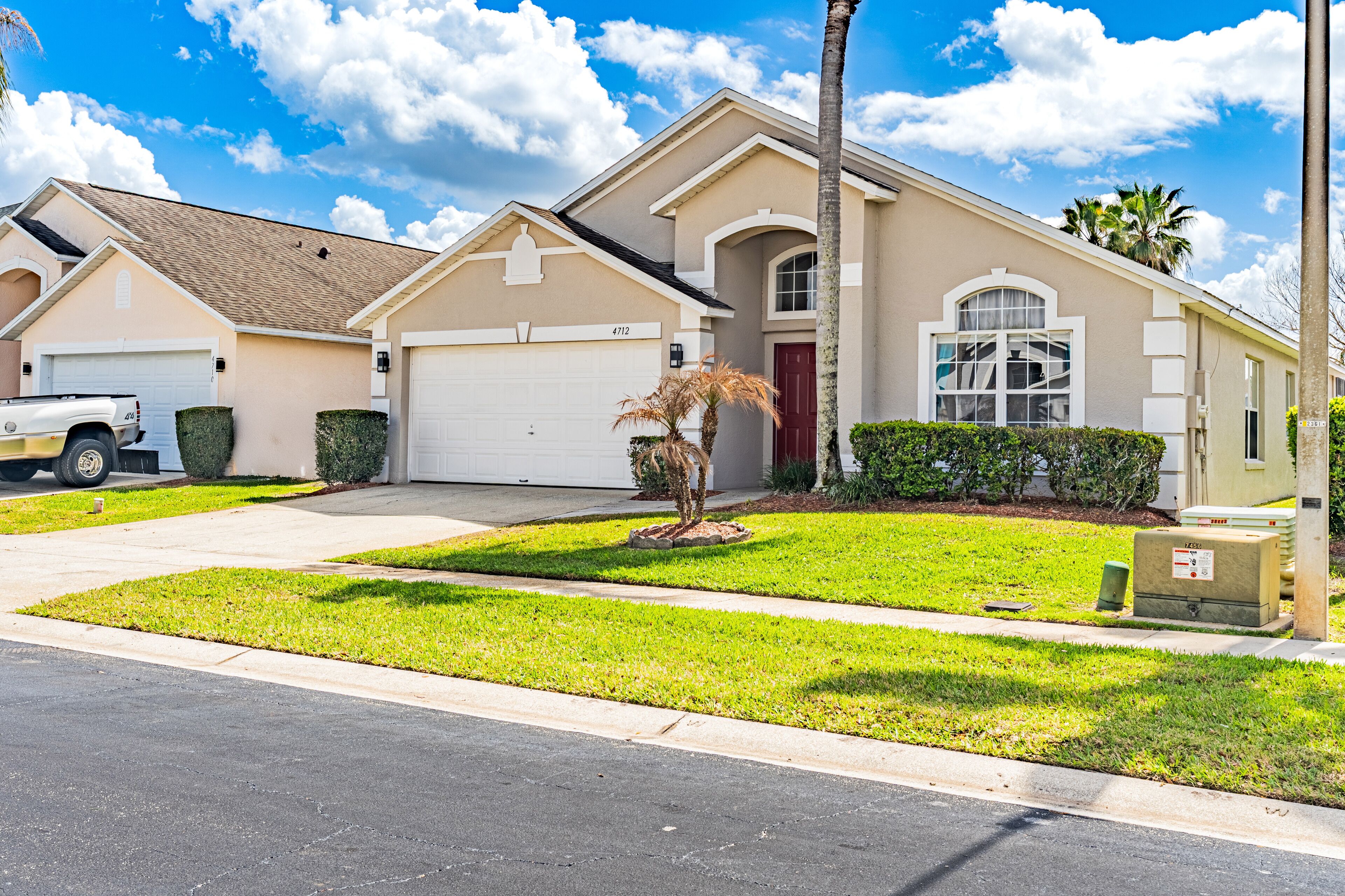 A residential house with a garage, a driveway, and a well-maintained lawn.